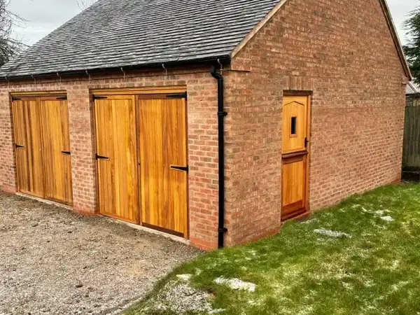 Brick outbuilding with timber double doors and a slate roof