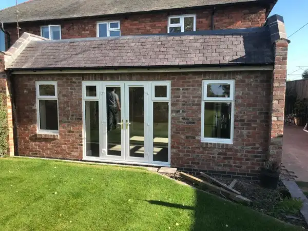 Single storey brick side extension with white French doors opening onto the lawn