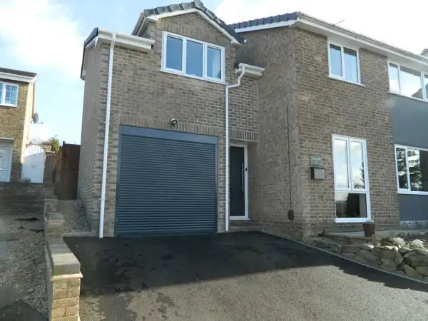 Side extension with an integral garage on a rendered house, viewed from the drive