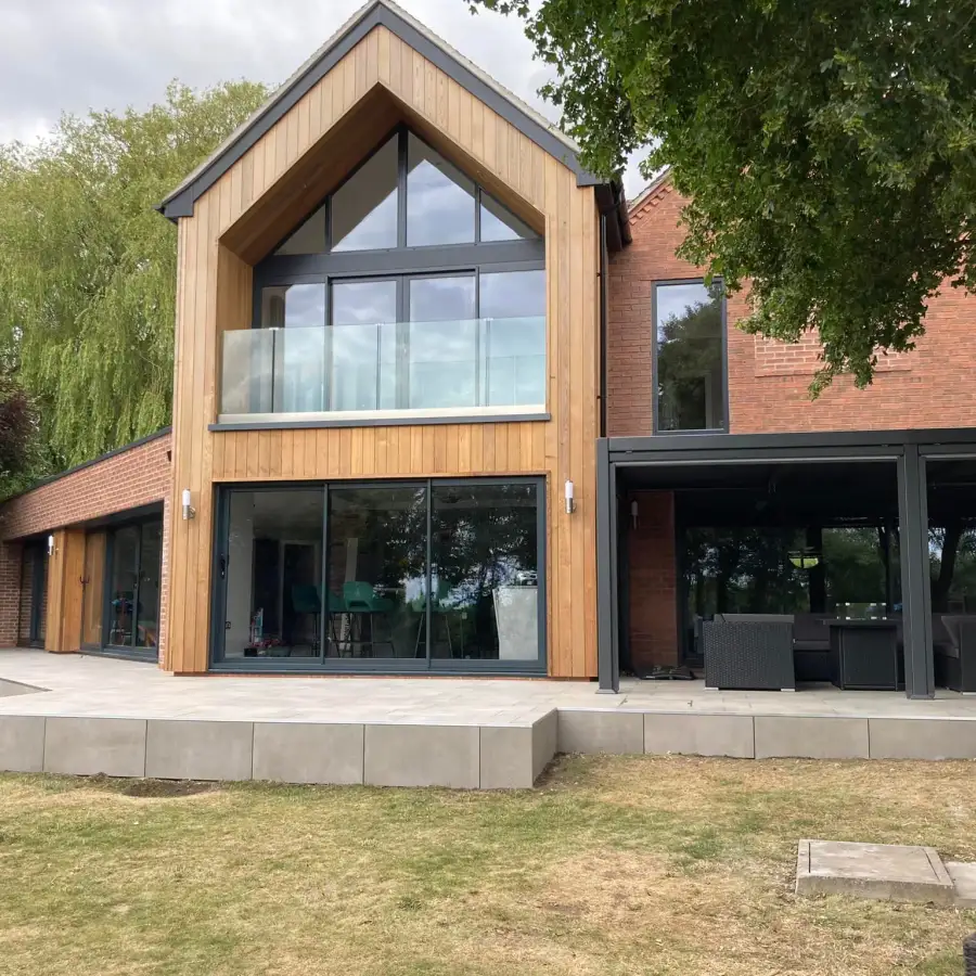 Timber-clad gable extension with full-height apex glazing and a Juliet balcony